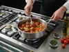 Stalowa patelnia głęboka Demeyere Industry z potrawą na kuchence gazowej