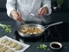 Stalowa patelnia Demeyere Industry 5-Ply z pierożkami na kuchence.