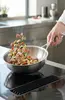Stalowa patelnia sauté Demeyere Industry z jedzeniem w powietrzu
