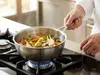 Stalowa patelnia sauté Demeyere Industry z warzywami na kuchence gazowej.