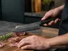 Ręcznie kuty nóż Santoku Suncraft Senzo Retro z ostrzem GIN-SAN 16,7 cm na tle kuchni.