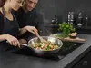 Stalowy wok Demeyere Specialities, 26 cm, z warzywami na kuchence indukcyjnej.