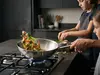 Wok Demeyere Specialities na kuchence gazowej, z warzywami i mięsem w powietrzu.