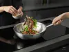 Wok Demeyere Specialities stalowy, 7-warstwowy, Ø 30 cm, z warzywami i mięsem na kuchence.