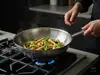 Stalowy wok Demeyere Specialities z warzywami na kuchence gazowej.