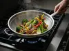 Stalowy wok Demeyere Specialities na kuchence z warzywami i mięsem, Ø 36 cm.