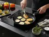 Patelnia Scanpan Urban z tytanowo-ceramiczną powłoką, smażąca warzywa i ser na kuchence.