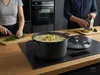 Tytanowo-ceramiczny garnek Pro SB+ Scanpan z pokrywką, 3,5 litra, w kuchni podczas gotowania.