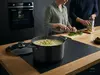 Tytanowo-ceramiczny garnek Scanpan Pro SB+ 4,8 l z pokrywką na drewnianym blacie w kuchni