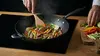 Tytanowo-ceramiczny wok Pro SB+ marki Scanpan na drewnianym blacie z warzywami.