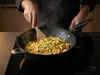 Tytanowo-ceramiczny wok Scanpan Pro SB+ z aromatycznym daniem na kuchence.