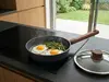 Patelnia Woll z jajkami sadzonymi i szparagami na nowoczesnej kuchence indukcyjnej.