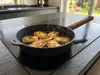 Patelnia WOLL z grillowanym serem i granatem na płycie indukcyjnej w nowoczesnej kuchni.