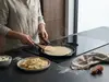 Patelnia producenta na indukcji z naleśnikiem i świeżymi składnikami w tle.