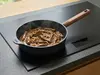 Głęboka patelnia tytanowa Eco Logic QXR Wood WOLL z drewnianym uchwytem na kuchence indukcyjnej.
