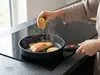 Produkt. Patelnia z łososiem i cytryną na nowoczesnej kuchence indukcyjnej.