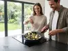 Produkt kuchenny – patelnia Produkt z warzywami na płycie indukcyjnej, w jasnej kuchni