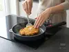 Patelnia produkt z rumianym kotletem na kuchence indukcyjnej.
