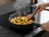 Patelnia WOLL Eco Logic QXR z odpinanym uchwytem podczas smażenia gnocchi na kuchence indukcyjnej.