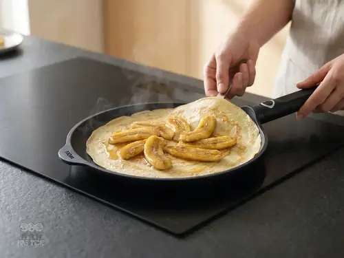 Tytanowa patelnia Eco Logic QXR WOLL z powłoką nieprzywierającą, Ø 26 cm, na kuchni z naleśnikiem.