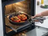 Wnętrze piekarnika z naczyniem Produkt i faszerowanymi paprykami.