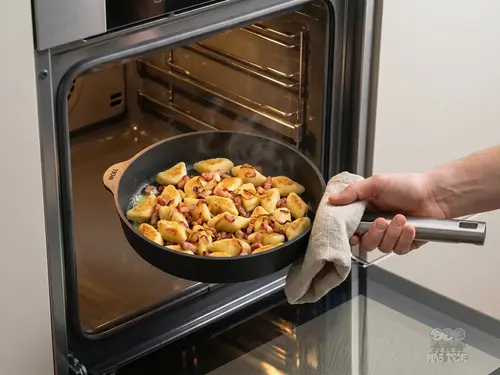 Patelnia produkt z pieczonymi pierogami i boczkiem, wyjmowana z piekarnika.