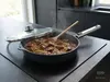 Patelnia produkt z pokrywką, dusząca mięso z cebulą na kuchennym blacie.