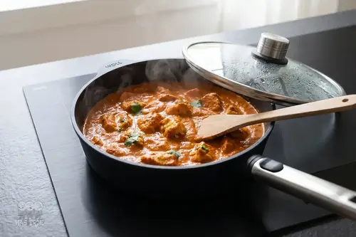 Głęboka patelnia tytanowa WOLL Eco Logic QXR PRO z daniem curry na kuchence.