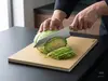 Nóż Suncraft Elegancia Santoku przecinający kapustę na desce.
