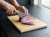 Nóż Santoku Suncraft Elegancia, stal SG2, kroi cebulę na desce.