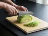Nóż Santoku Suncraft Elegancia krojący kapustę na desce kuchennej.