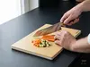 Mistrzowski nóż Santoku Suncraft Elegancia krojący warzywa na desce.