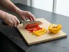 Senzo Black Suncraft – japoński nóż Santoku 33-warstwowy VG-10, krojenie papryki na desce kuchennej.