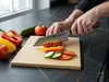 Czerniony nóż Bunka Suncraft Senzo Black 33-warstwowy VG-10 krojący warzywa na kuchennym blacie.