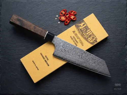 Japoński nóż Bunka Senzo Black Suncraft na kamieniu wodnym z papryczką chili na ciemnym tle, 33 warstwy VG-10