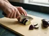 Japoński nóż Ko-Deba Senzo Classic Suncraft tnie bakłażana na jasnej desce kuchennej w świetle dziennym