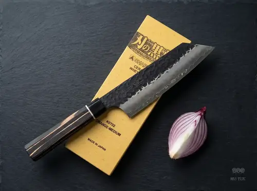 Senzo Finest Suncraft Bunka 16,5 cm – japoński nóż SPG STRIX na ostrzałce, obok połówka czerwonej cebuli