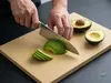 Suncraft Senzo Professional – japoński nóż Santoku SG2, 16,5 cm kroi awokado na desce kuchennej.