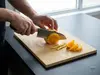 Japoński nóż Santoku Suncraft Senzo Professional SG2, 16,5 cm, krojenie pomarańczy na desce kuchennej