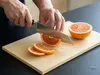 Japoński nóż Bunka Suncraft Senzo Professional, stal SG2, kroi grejpfruta na desce kuchennej