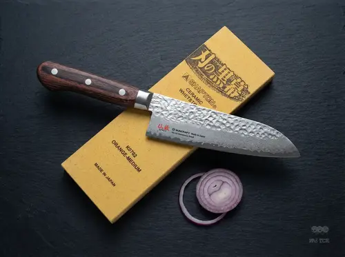 Japoński nóż Santoku Suncraft Senzo Universal z 33 warstwami, europejska rękojeść, 16,5 cm, na tle osełki
