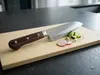 Nóż Santoku Suncraft Senzo Universal 33-warstwowy, 16,5 cm na desce z pokrojonymi warzywami w kuchni.