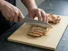 Suncraft Senzo Universal, 33-warstwowy japoński nóż Santoku z europejską rękojeścią, kroi mięso na desce.