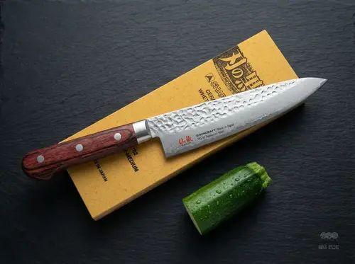 Japoński nóż kucharza Suncraft Senzo Universal Gyuto 18 cm z europejską rękojeścią na tle ostrzałki