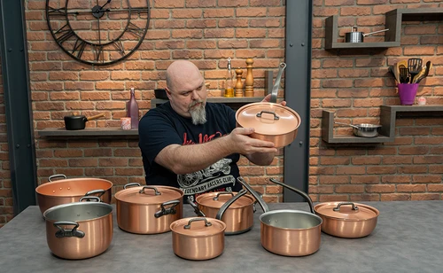 Zestaw garnków kuchennych produkt ustawiony na blacie, mężczyzna prezentuje jeden z garnków na tle ceglanej ściany